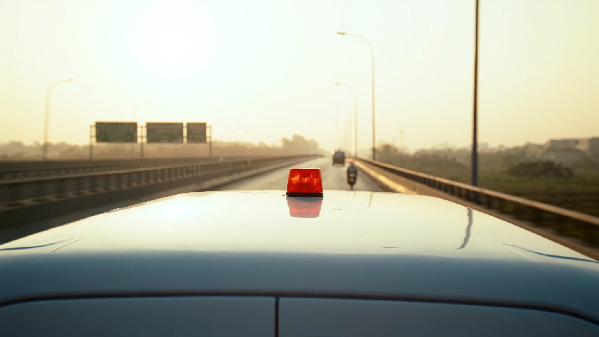 Illustrative image of an ambulance with an emergency beacon on an elevated highway at sunrise